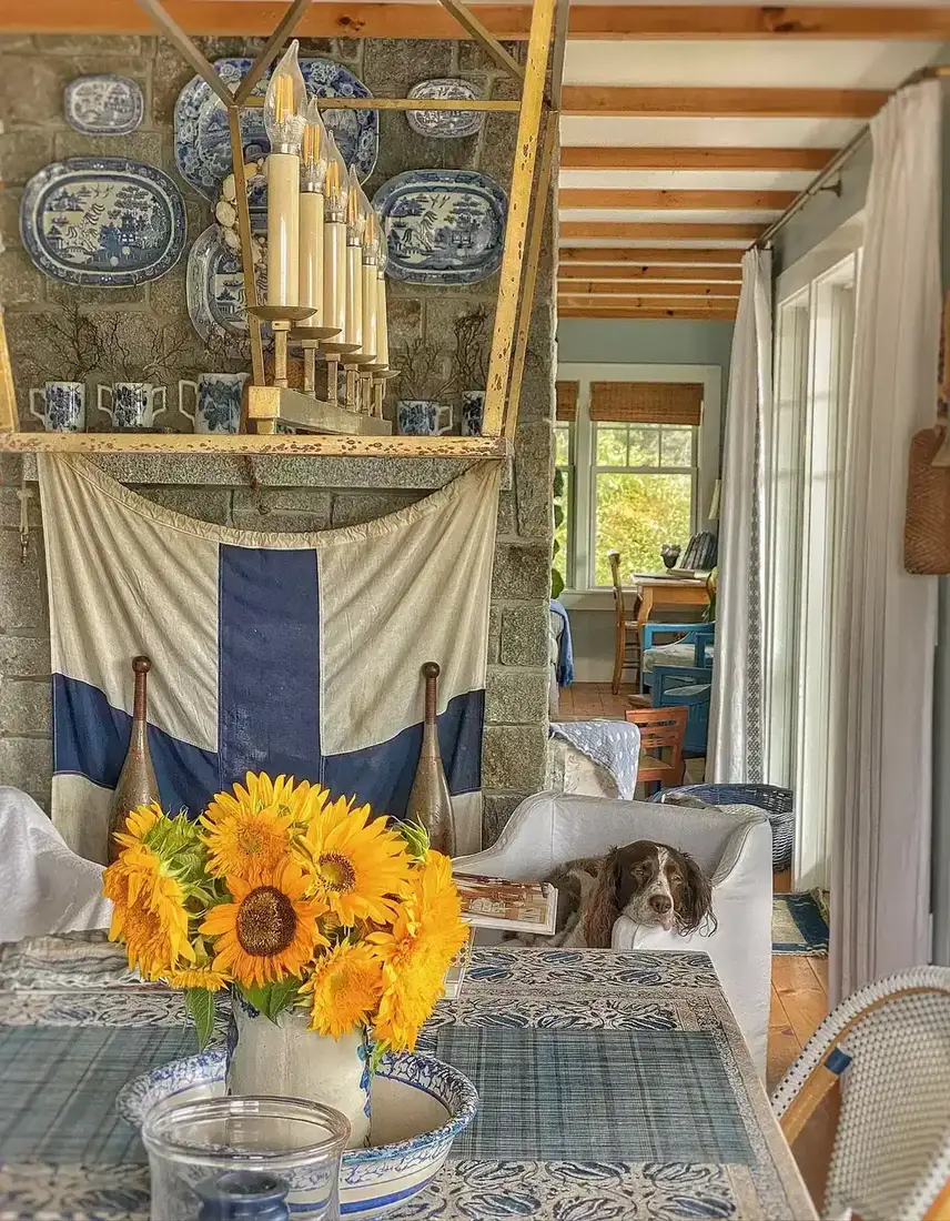 Blue and white mantel decor against a stone fireplace with layered textiles