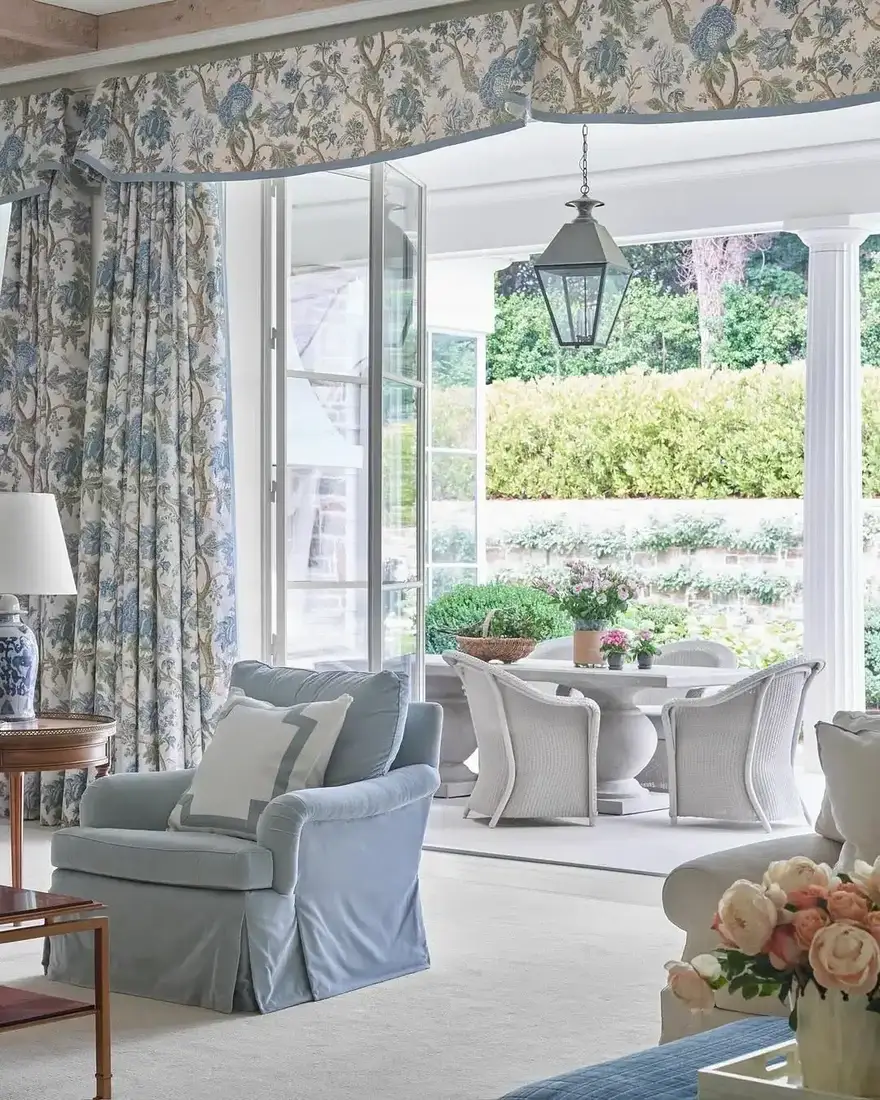 Sunroom with blue floral curtains framing tall windows