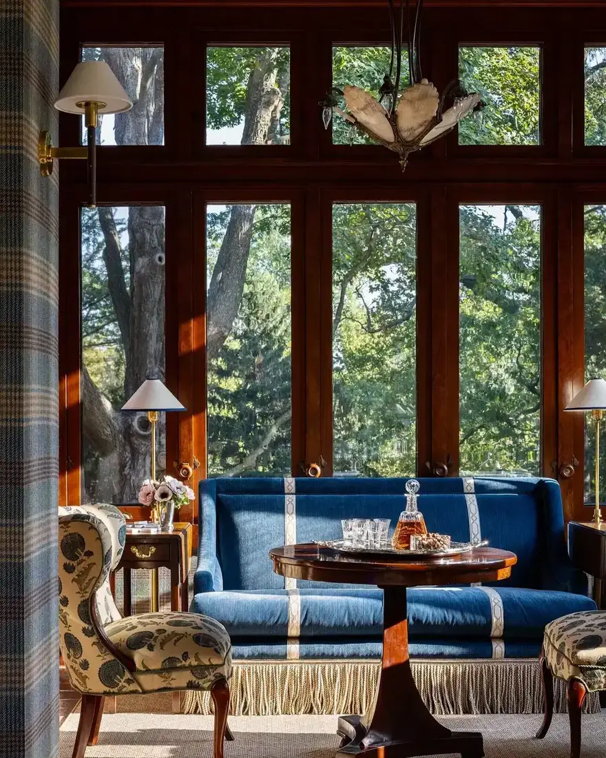 Blue fringe sofa in bright sunroom window bay
