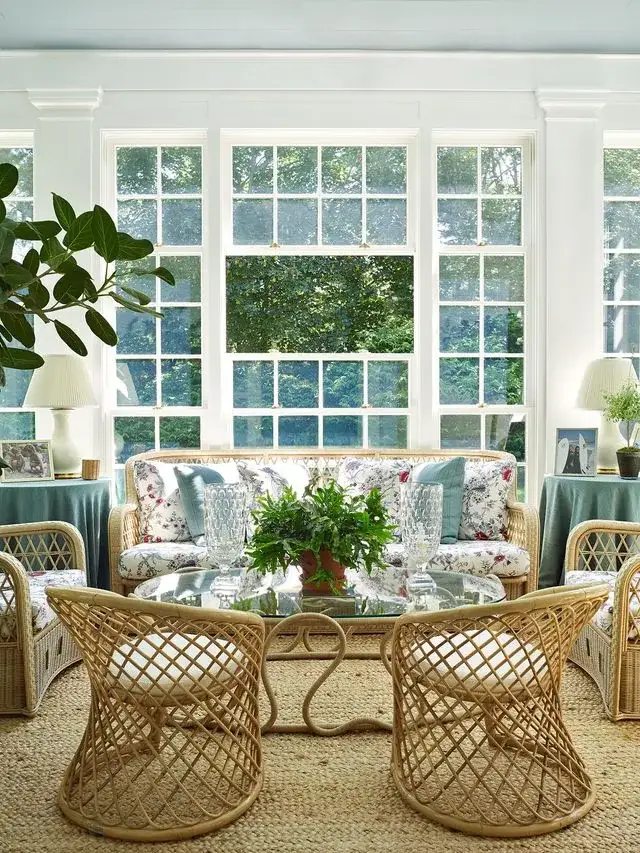 Bright white sunroom with natural rattan furniture and soft cushions