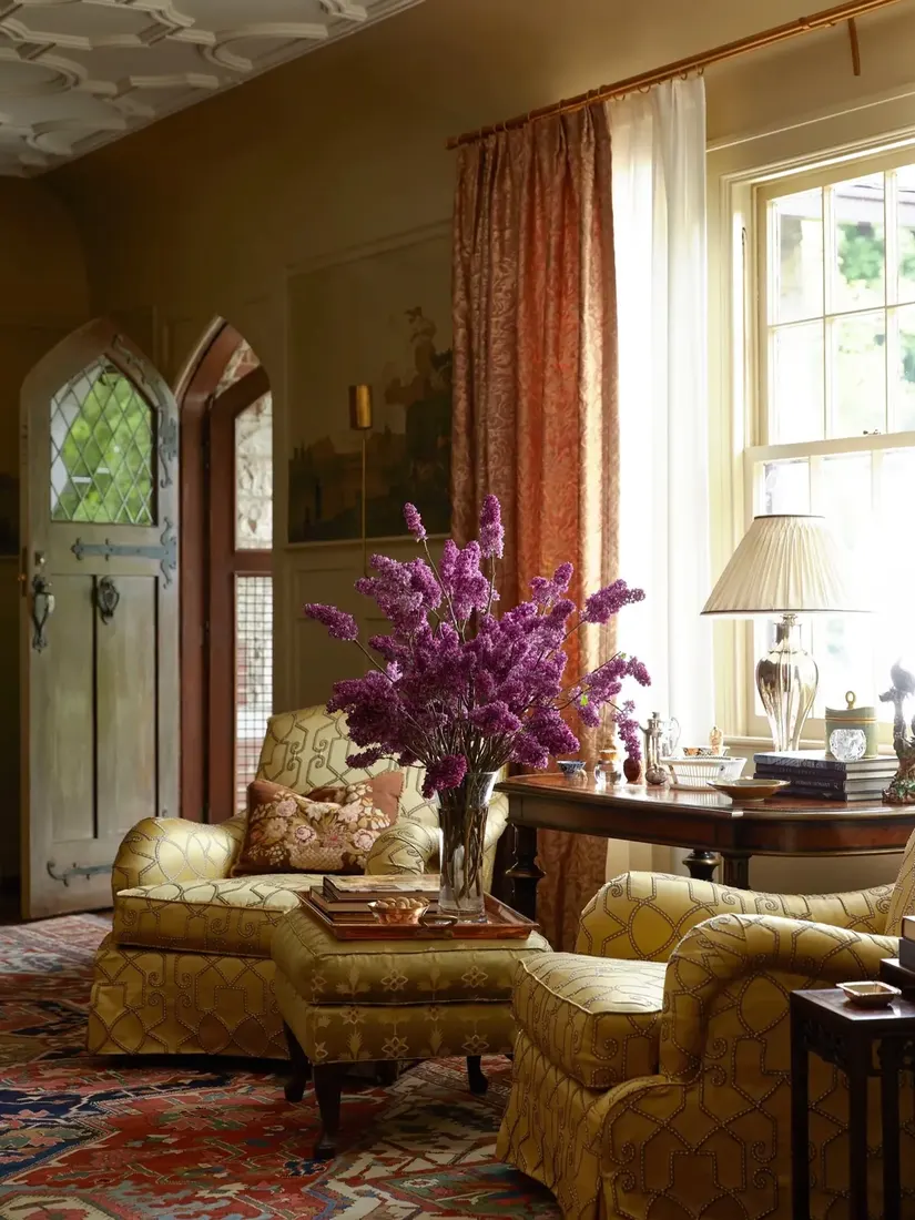 Olive sitting room with gothic arched door and lilacs in vase