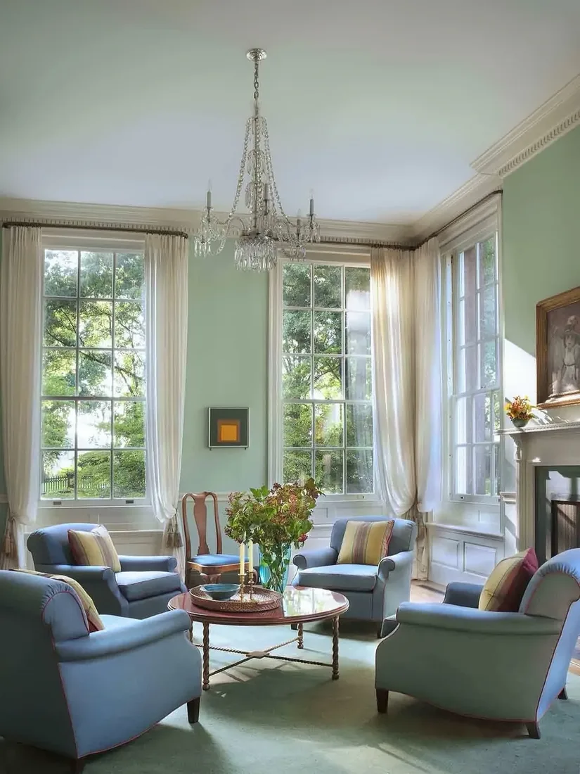 Pale green sitting room with pair of blue armchairs and fireplace
