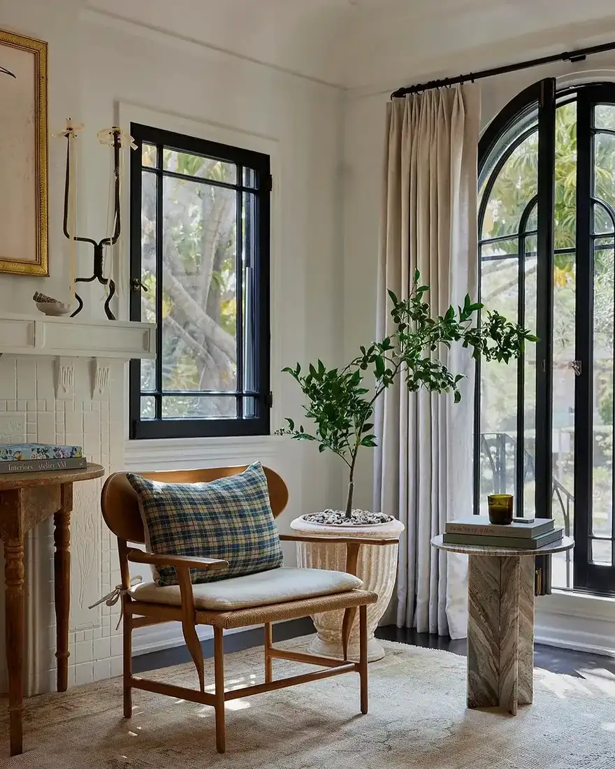 White sitting room with arched black windows and pale linen seating