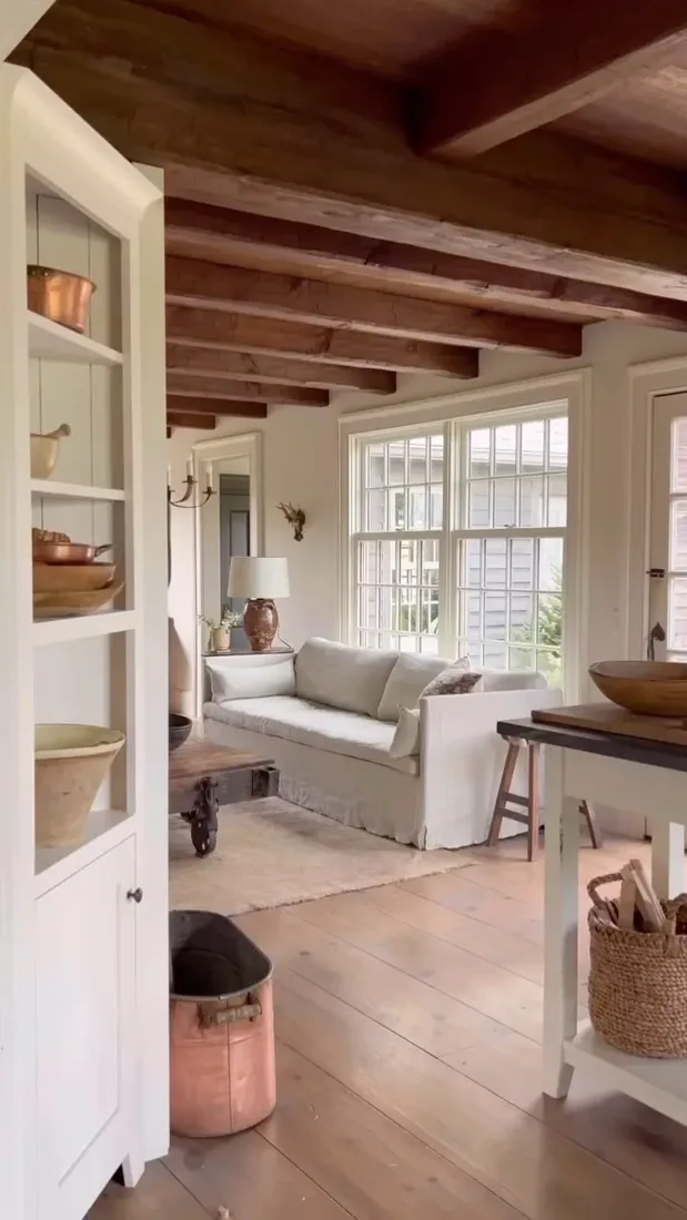 Vaulted living room with timber beams, pale ceiling and soft textiles