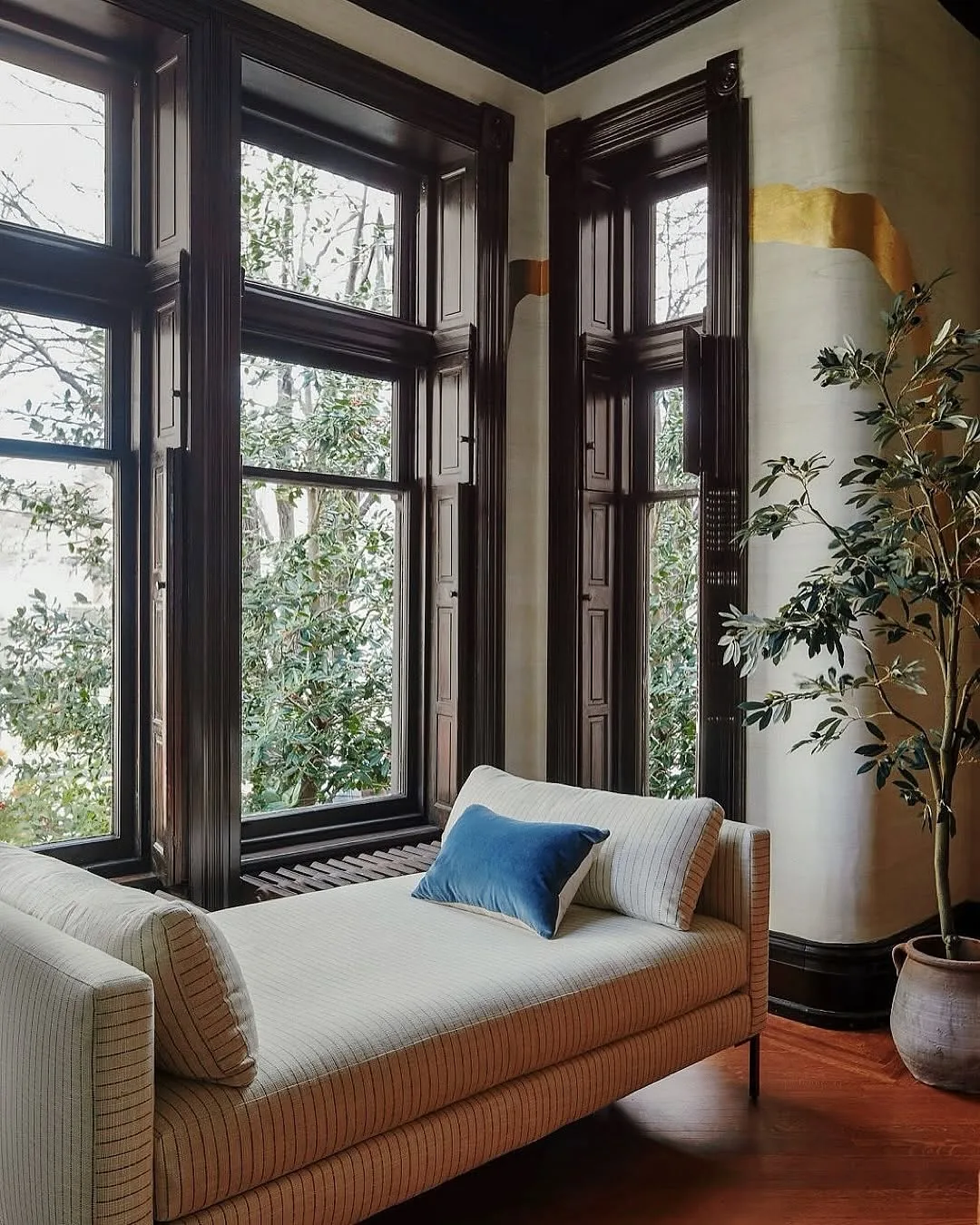 Dark wood window seat daybed against plaster walls