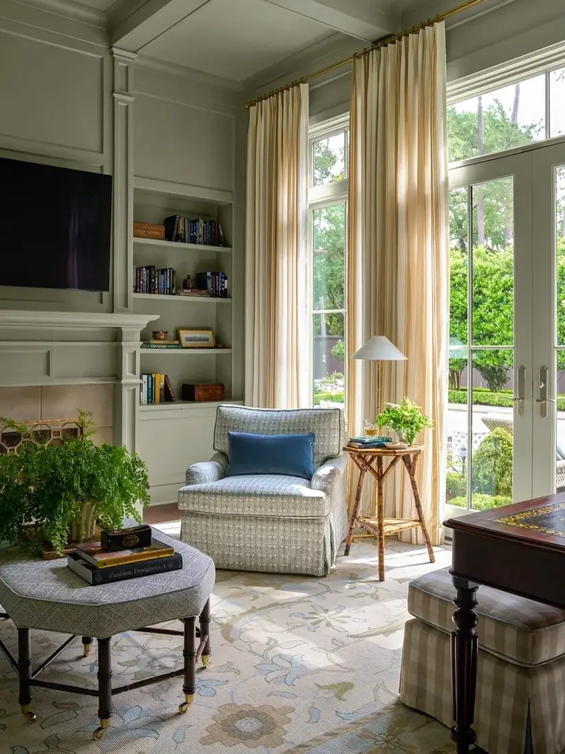 Sage green built-in bookcases in bright living room with arched door and calm styling