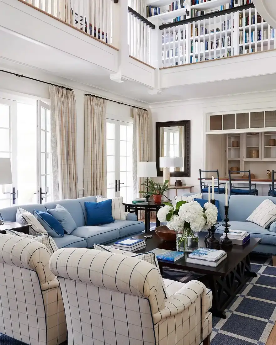 Two-story living room library with tall built-ins and balcony rail