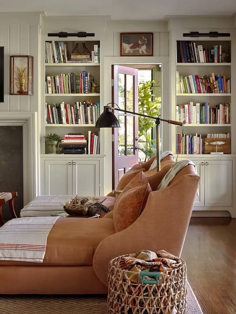 Warm peach living room bookshelves with soft light and layered decor